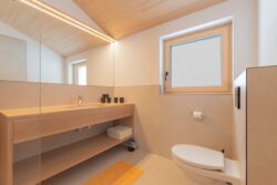 Waschbecken mit großformatigem Wandspiegel und WC der Ferienwohnung BergZeit in Schoppernau